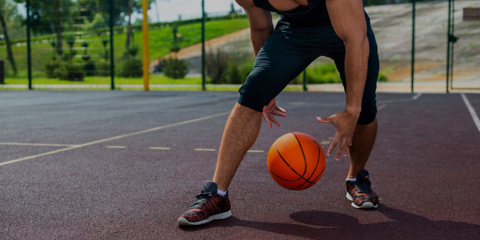 athlete dribbling basketball on outdoor court during practice session